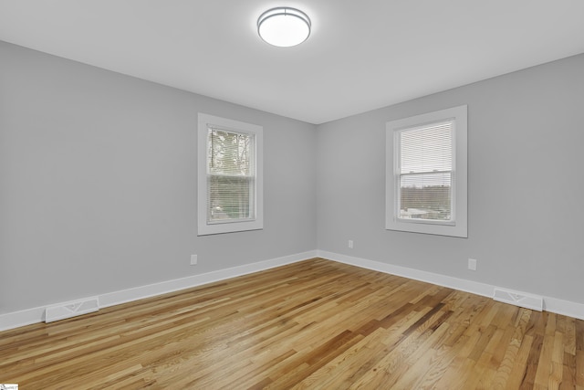 spare room featuring visible vents, baseboards, and wood finished floors