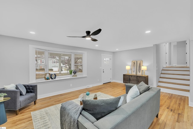 living room featuring baseboards, stairs, recessed lighting, light wood-style flooring, and a ceiling fan