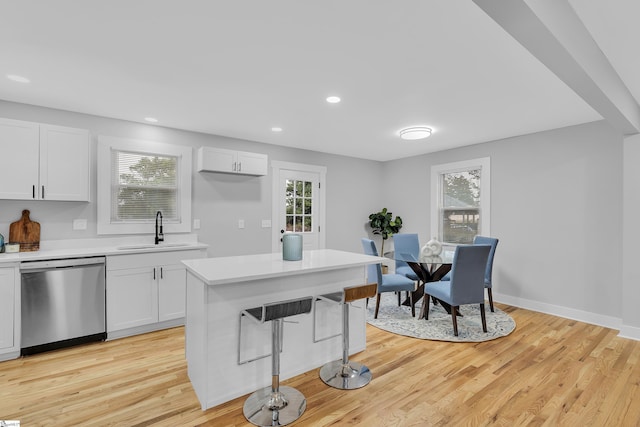 kitchen with dishwasher, light wood-type flooring, light countertops, white cabinets, and a sink