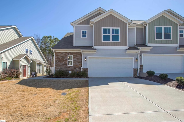 view of front facade with concrete driveway, an attached garage, stone siding, and a front yard