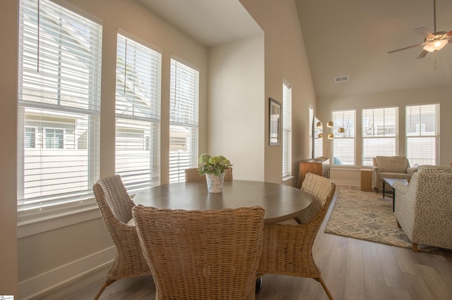 dining space with visible vents, lofted ceiling, a ceiling fan, wood finished floors, and baseboards