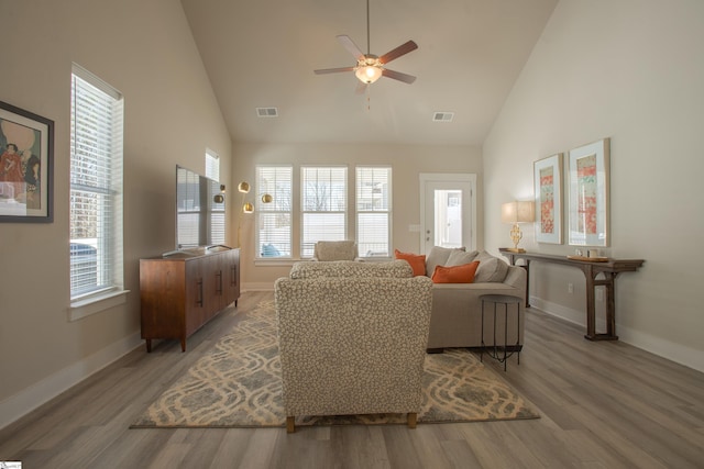 living room with visible vents, high vaulted ceiling, baseboards, and wood finished floors