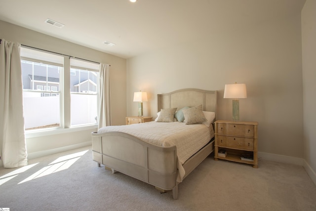 bedroom featuring visible vents, light carpet, and baseboards