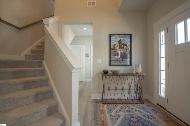 entryway featuring stairway, wood finished floors, visible vents, and baseboards