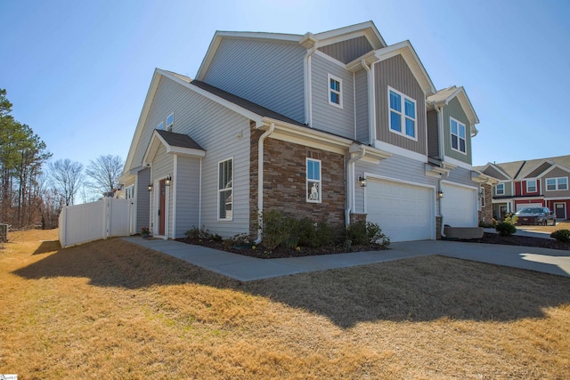 view of property exterior with a lawn, stone siding, fence, concrete driveway, and an attached garage