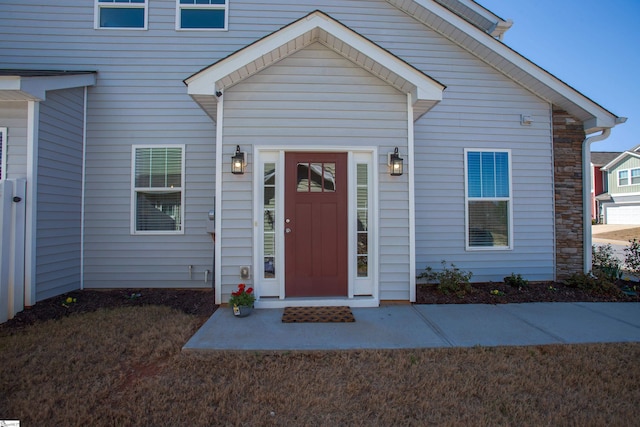 view of exterior entry with stone siding and a yard