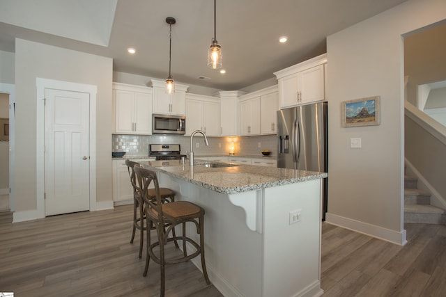 kitchen with a sink, appliances with stainless steel finishes, a breakfast bar area, white cabinets, and decorative backsplash