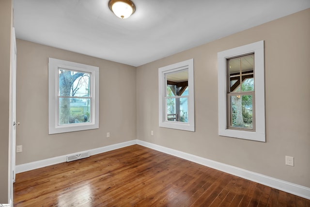 empty room with visible vents, wood-type flooring, and baseboards