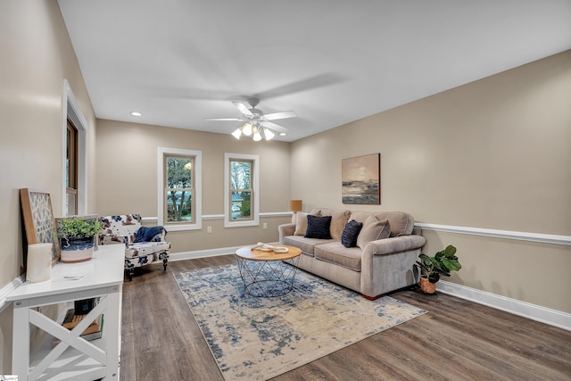 living area featuring dark wood-style floors, a ceiling fan, and baseboards