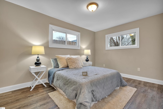 bedroom with multiple windows, wood finished floors, and baseboards