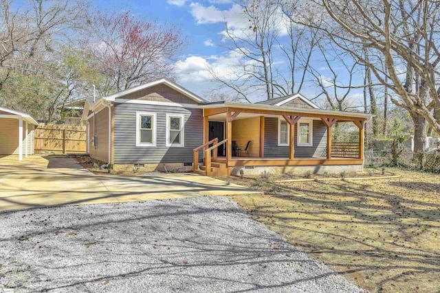 view of front of property with a porch, fence, driveway, and crawl space