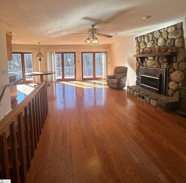 living area with a textured ceiling, a healthy amount of sunlight, wood finished floors, and a fireplace