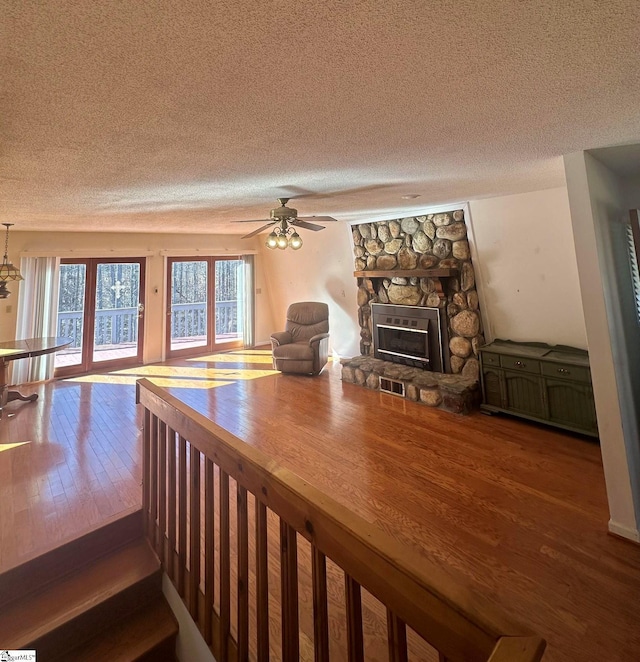 unfurnished living room with a ceiling fan, visible vents, a fireplace, wood-type flooring, and a textured ceiling