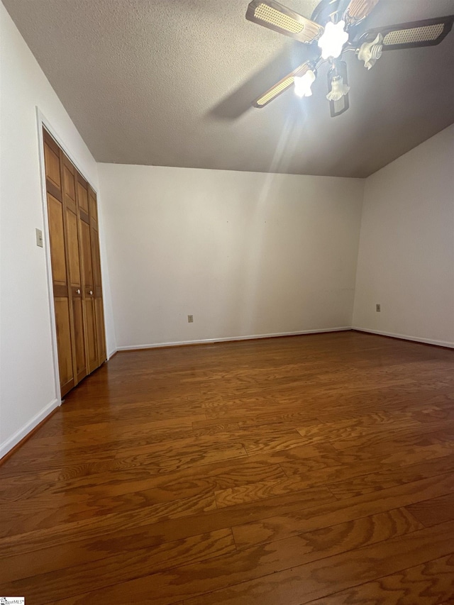 empty room with baseboards, a textured ceiling, dark wood-type flooring, and ceiling fan