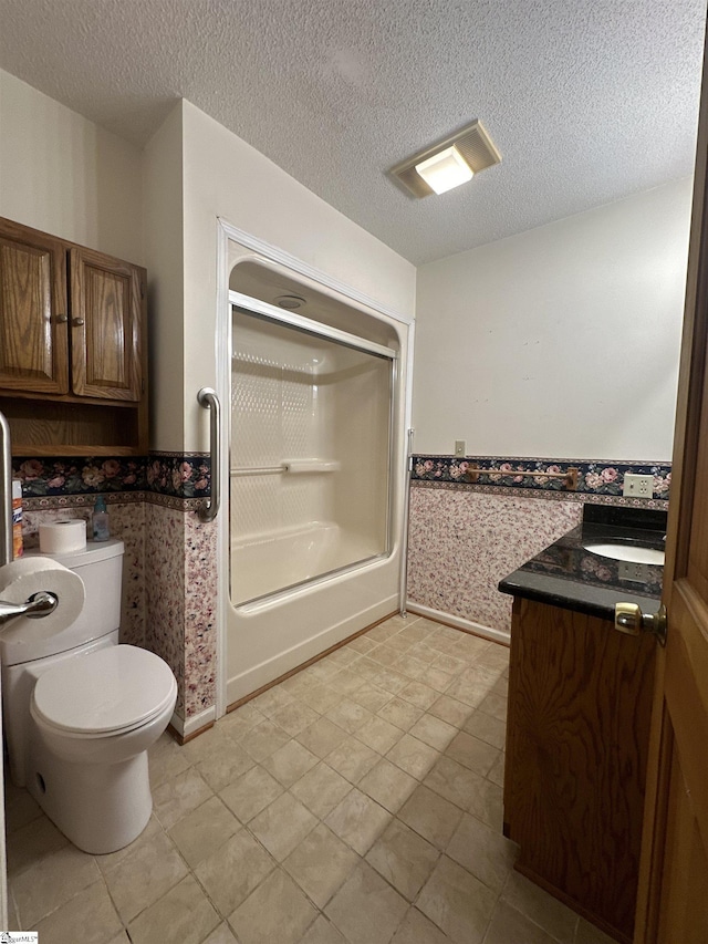 full bathroom featuring wallpapered walls, toilet, a wainscoted wall, and a textured ceiling