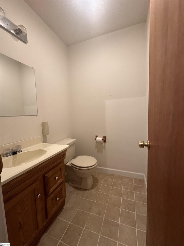 bathroom with baseboards, toilet, vanity, and tile patterned flooring