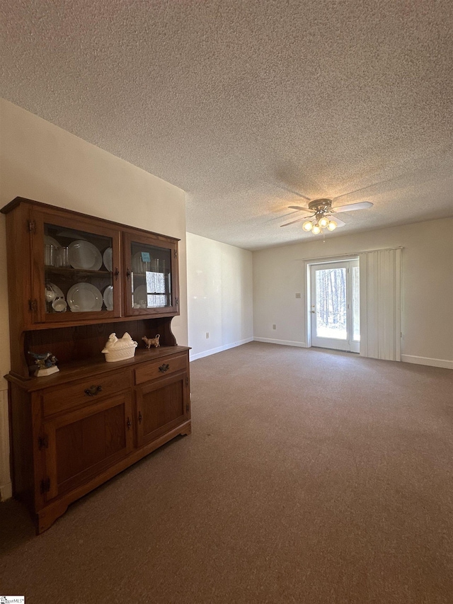 living area featuring light colored carpet, a textured ceiling, baseboards, and ceiling fan