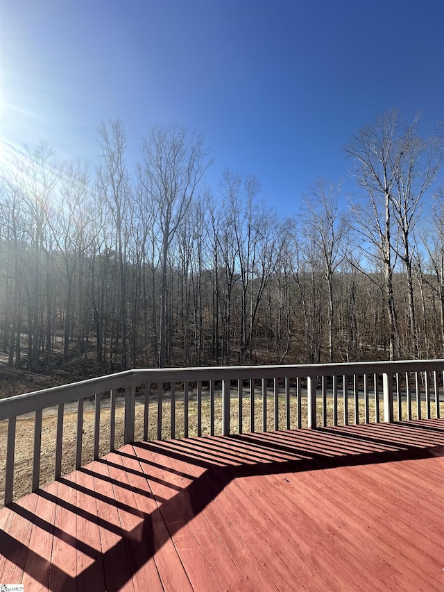 wooden terrace featuring a wooded view