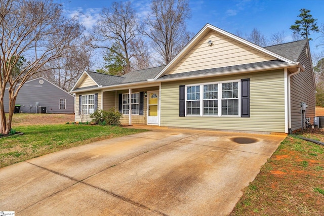 single story home with central AC unit, a shingled roof, and a front yard