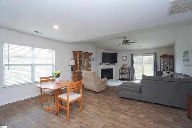 dining area featuring visible vents, wood finished floors, a glass covered fireplace, and a ceiling fan