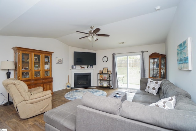 living room featuring visible vents, dark wood-type flooring, a fireplace, lofted ceiling, and ceiling fan