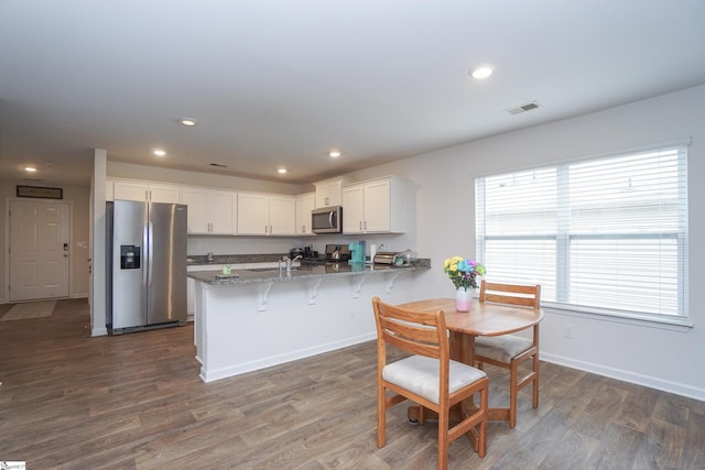 kitchen featuring visible vents, white cabinetry, appliances with stainless steel finishes, a peninsula, and dark wood-style flooring