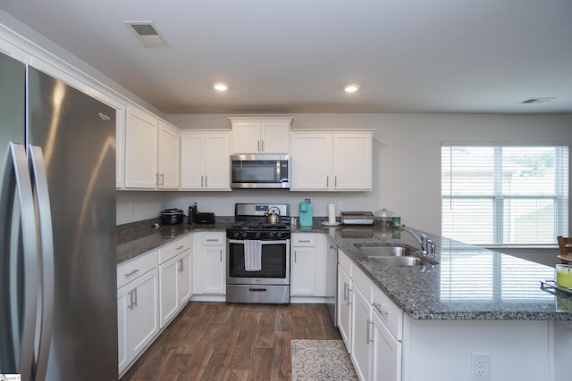 kitchen featuring visible vents, a peninsula, a sink, dark wood-type flooring, and appliances with stainless steel finishes