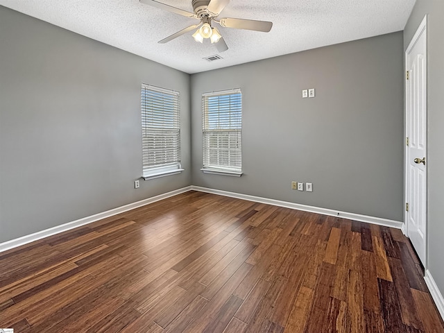spare room featuring a ceiling fan, baseboards, visible vents, dark wood-type flooring, and a textured ceiling