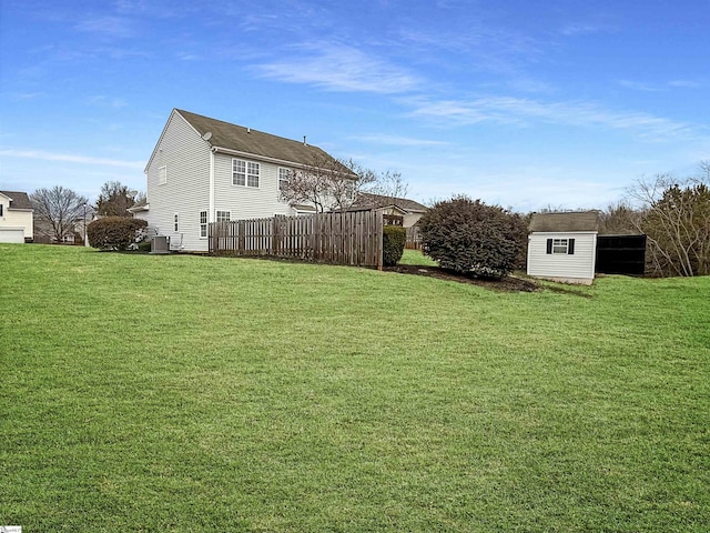 view of yard with an outbuilding, central AC, fence, and a shed