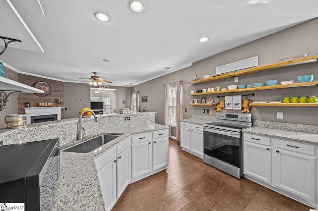 kitchen with a fireplace, open shelves, stainless steel electric range, and a sink