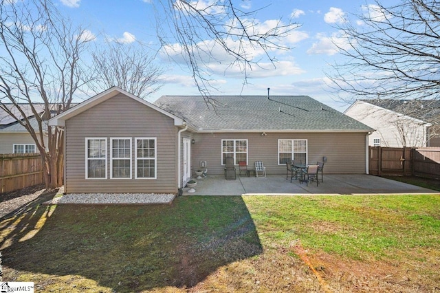 back of house with a fenced backyard, a lawn, a shingled roof, and a patio