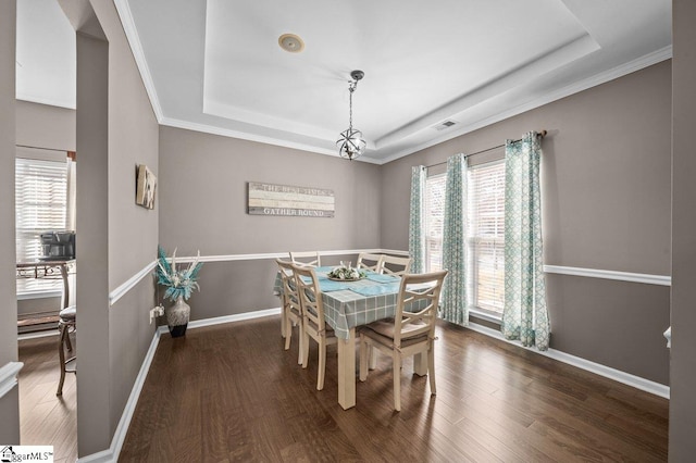 dining area featuring visible vents, a raised ceiling, a healthy amount of sunlight, and wood finished floors