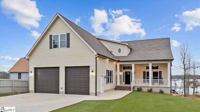 traditional-style house with an attached garage, covered porch, a shingled roof, concrete driveway, and a front lawn