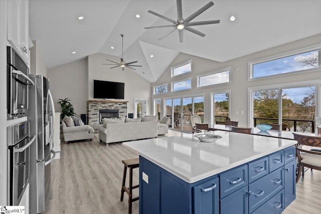 145 Brady Dr, Anderson, SC 29626 - kitchen with light wood finished floors, a stone fireplace, a kitchen breakfast bar, and blue cabinets