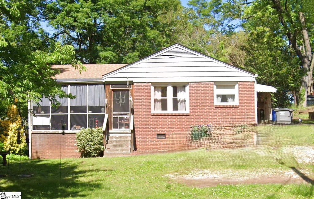 back of property featuring a yard, brick siding, a sunroom, and crawl space