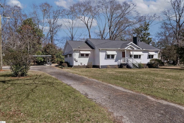 view of front of home featuring a front lawn, aphalt driveway, roof with shingles, a chimney, and a carport