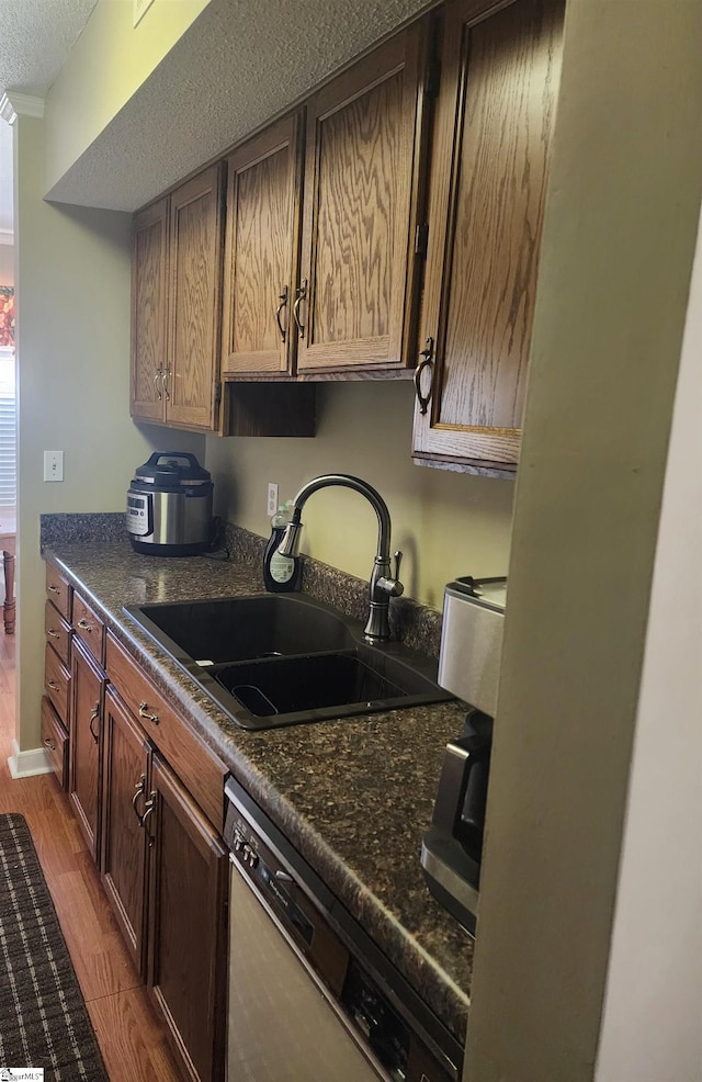 kitchen featuring dark countertops, dishwasher, wood finished floors, and a sink