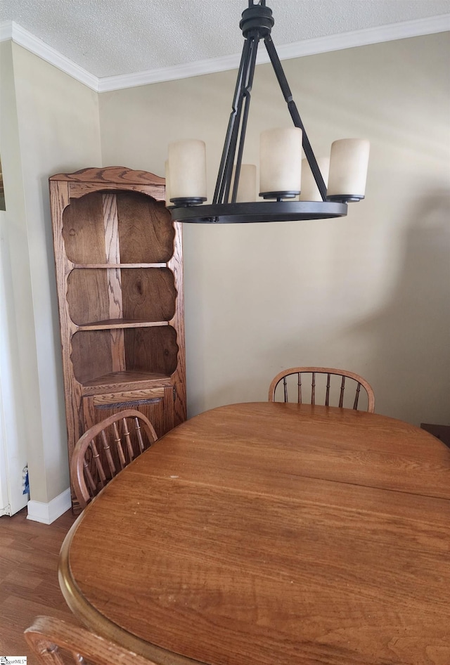 dining space featuring crown molding, wood finished floors, baseboards, and a textured ceiling