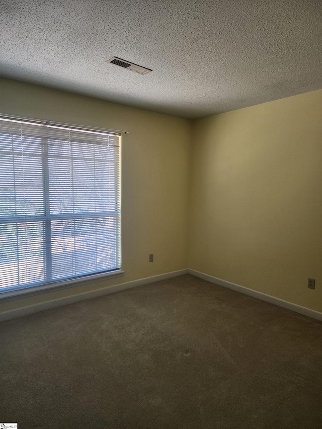 empty room with visible vents, baseboards, a textured ceiling, and carpet flooring