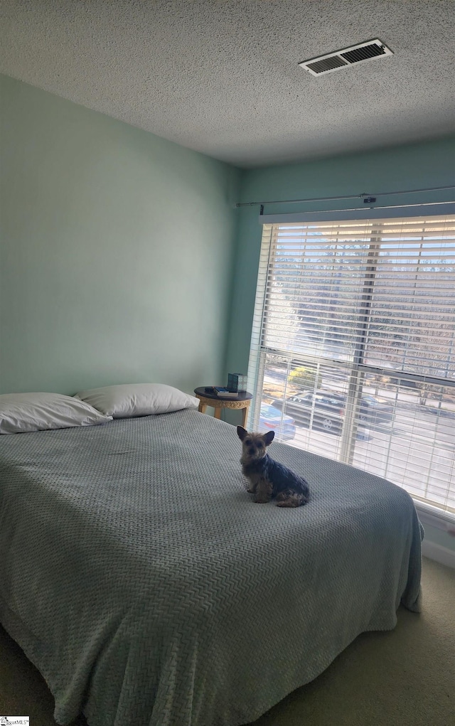 carpeted bedroom with visible vents and a textured ceiling