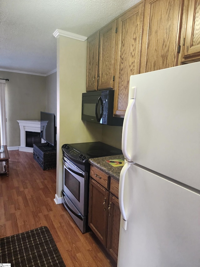 kitchen featuring dark wood-style floors, freestanding refrigerator, stainless steel range with electric cooktop, black microwave, and dark countertops