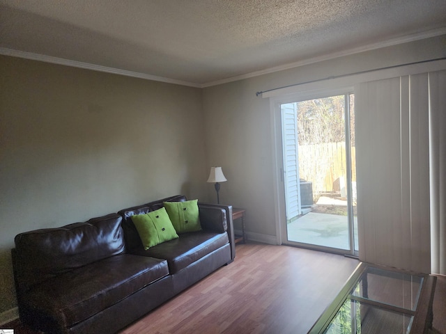 living area with baseboards, a textured ceiling, wood finished floors, and ornamental molding