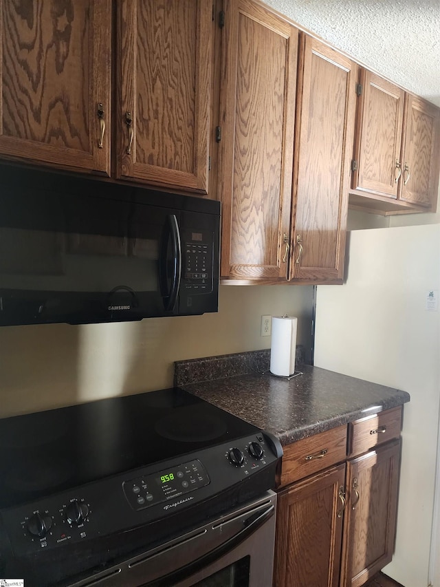 kitchen with black appliances, dark countertops, and brown cabinets