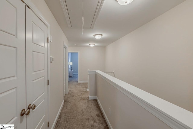 corridor featuring an upstairs landing, light carpet, attic access, and baseboards