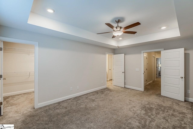 unfurnished bedroom with recessed lighting, a tray ceiling, baseboards, and carpet flooring