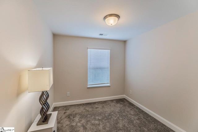 unfurnished room featuring visible vents, baseboards, and dark carpet