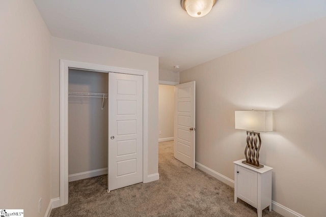 unfurnished bedroom with baseboards, carpet floors, and a closet