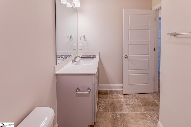 bathroom with toilet, vanity, and baseboards