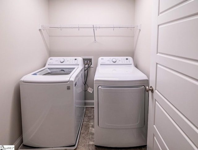 washroom with baseboards, separate washer and dryer, and laundry area