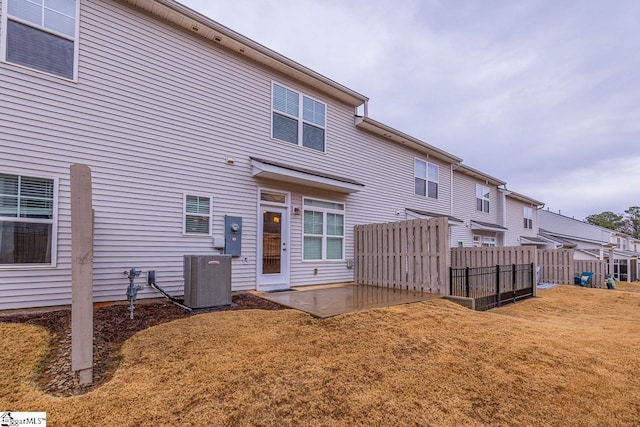 rear view of property featuring a patio area, central air condition unit, a yard, and fence